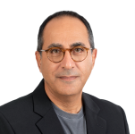 A man with short dark hair and glasses, wearing a dark blazer over a gray shirt, poses against a plain light background—ready to share insights on the evolving cybersecurity landscape in his latest video.